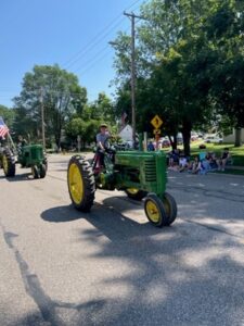 July 4th Tractor-Picture2 a person rides a green tractor with yellow wheels
