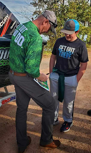 Fishing pro signs autograph for young male fan