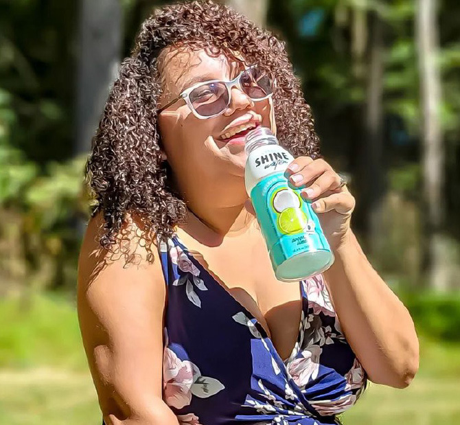 woman with sunglasses drinking a bottle of Shine