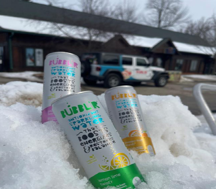 three cans of Bubbl'r sit in a snowbank while Bubbl'r Jeep is visible in the background