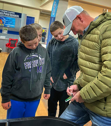fishing pro Kurt Walbeck signs autographs for 3 young male fans