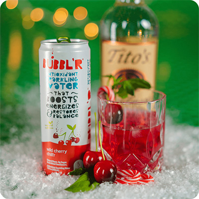 a can of wild cherry chill'r next to a glass of mixed merry cherry mix'r and a bottle of Tito's vodka