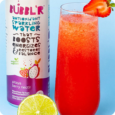 a can of pitaya berry nect'r next to a glass of mixed pitaya limeade cooler with a strawberry slice and a lime